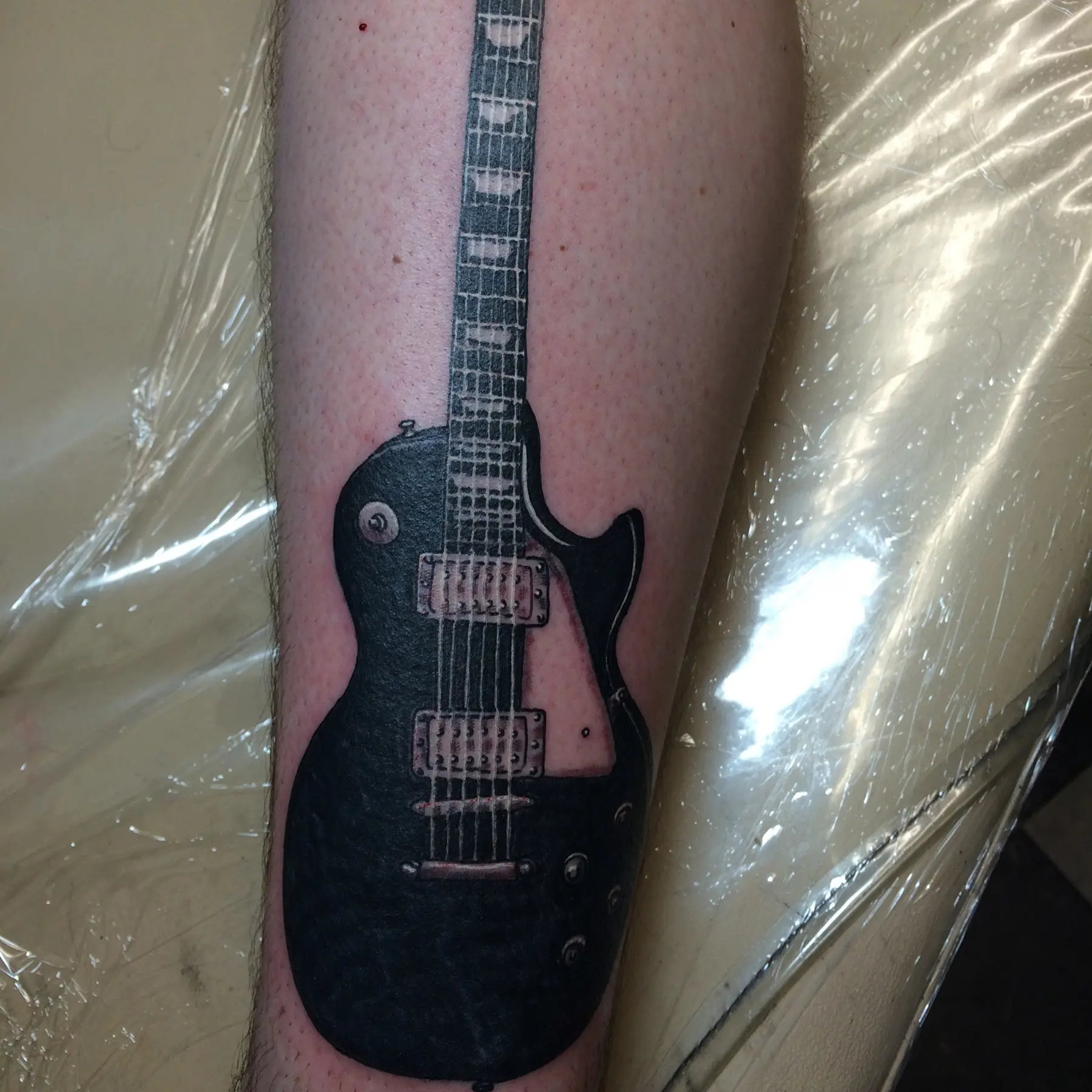 High-contrast black guitar tattoo by Josh Poindexter