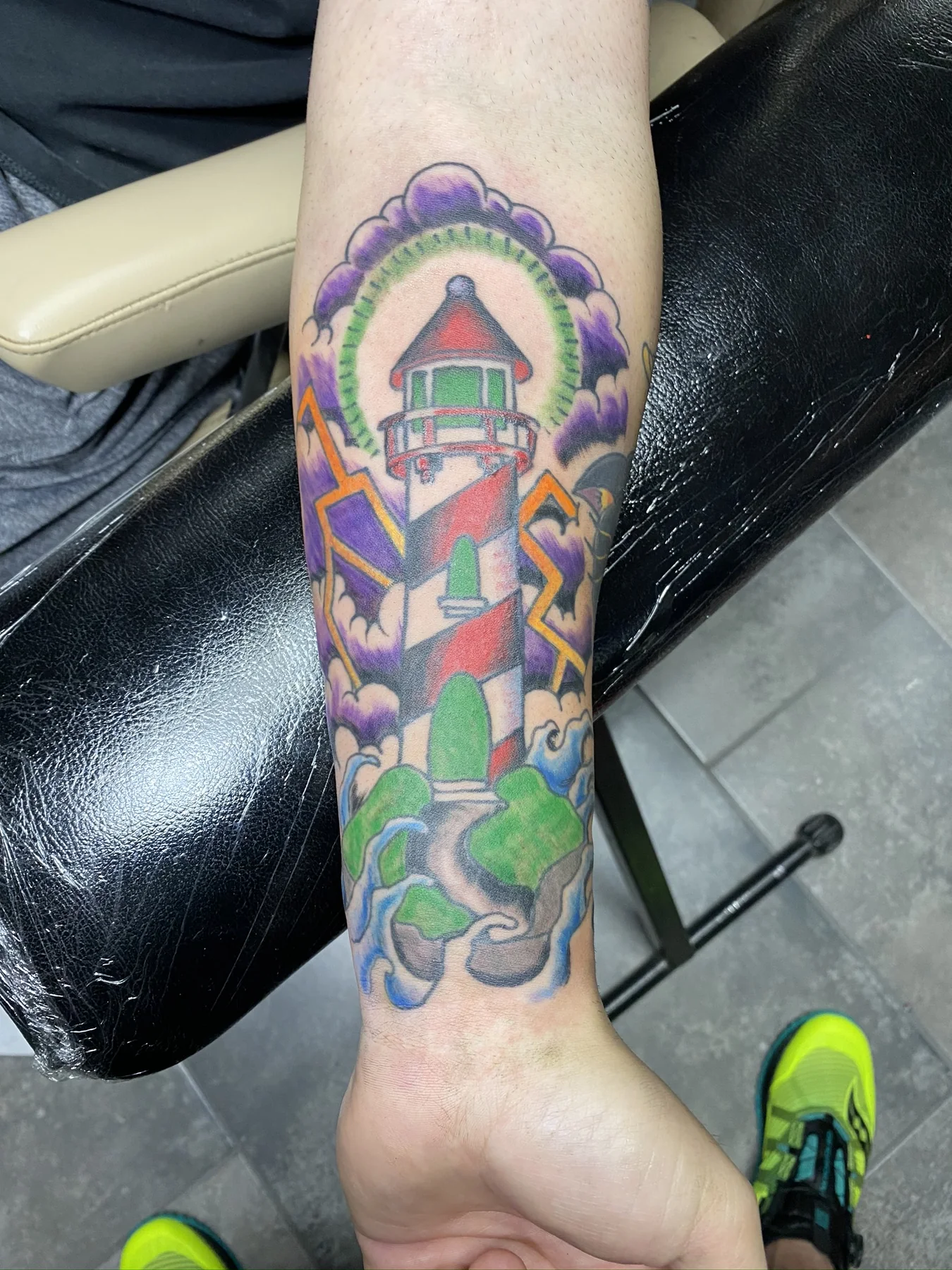 Bright illustrative lighthouse and ocean color tattoo by Josh Poindexter